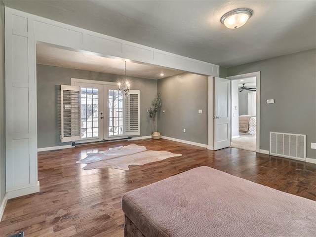 unfurnished bedroom featuring an inviting chandelier, dark hardwood / wood-style flooring, and french doors