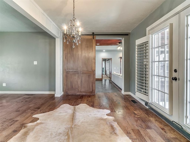 unfurnished dining area featuring dark wood-type flooring and a barn door