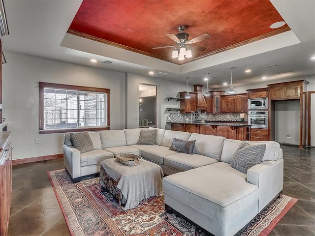 living room featuring crown molding, ceiling fan, a raised ceiling, and sink