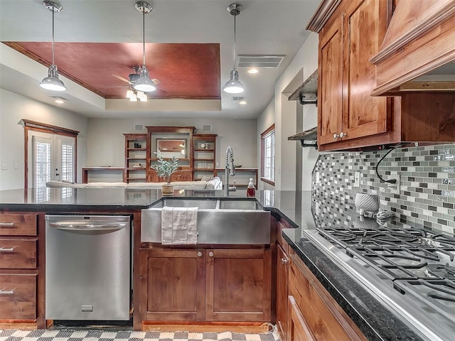 kitchen with pendant lighting, sink, backsplash, stainless steel appliances, and a tray ceiling