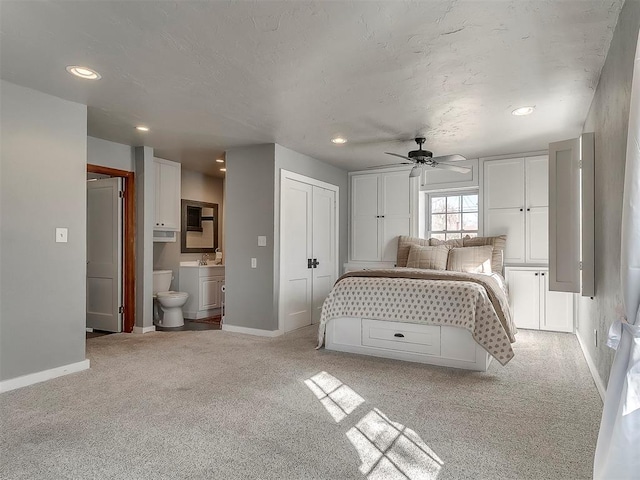 bedroom with sink, connected bathroom, light colored carpet, and ceiling fan