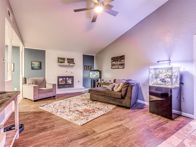 living room with lofted ceiling, hardwood / wood-style flooring, a fireplace, and ceiling fan