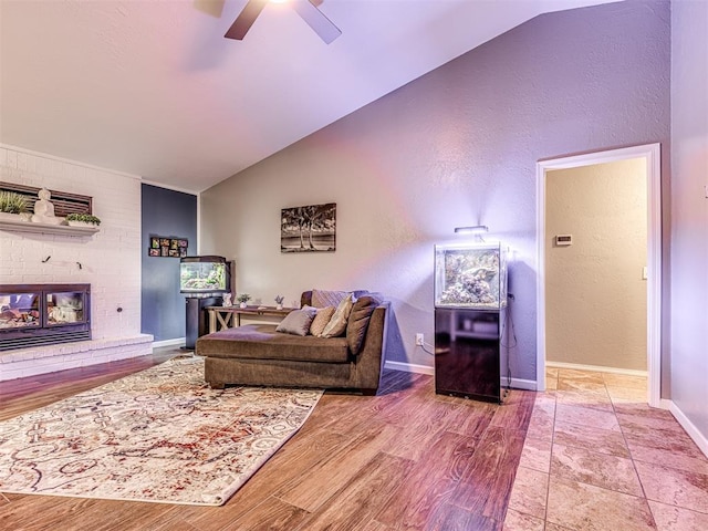 living room with lofted ceiling, a brick fireplace, hardwood / wood-style flooring, and ceiling fan