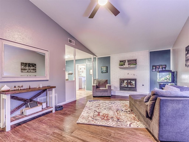 living room with lofted ceiling, a brick fireplace, hardwood / wood-style flooring, and ceiling fan