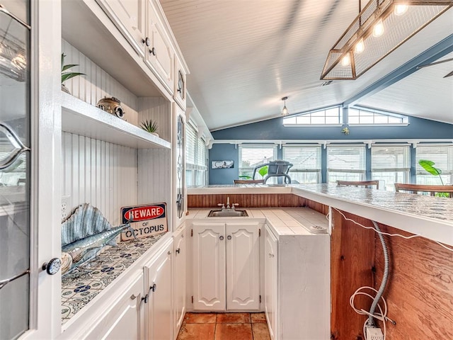 kitchen with vaulted ceiling with beams, sink, and white cabinets