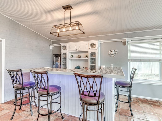 kitchen featuring white cabinetry, brick wall, and a kitchen breakfast bar