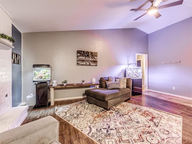 living room with a brick fireplace, hardwood / wood-style flooring, vaulted ceiling, and ceiling fan