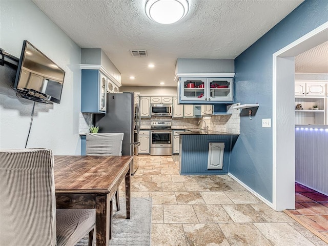 kitchen featuring sink, blue cabinetry, appliances with stainless steel finishes, white cabinetry, and tasteful backsplash