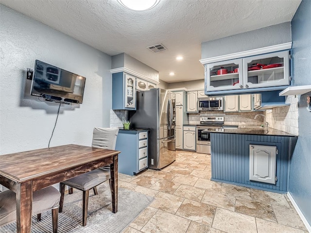 kitchen featuring tasteful backsplash, sink, stainless steel appliances, and a textured ceiling