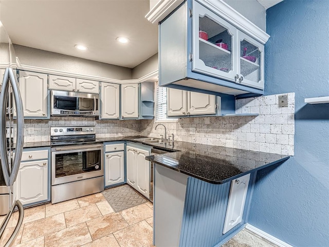 kitchen with sink, backsplash, kitchen peninsula, stainless steel appliances, and white cabinets