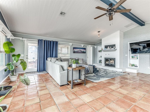 tiled living room with ceiling fan, a large fireplace, and lofted ceiling with beams