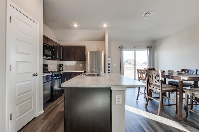 kitchen with sink, dark brown cabinets, black appliances, a center island with sink, and dark hardwood / wood-style flooring