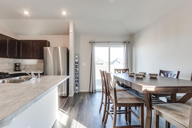 kitchen with vaulted ceiling, stainless steel refrigerator, sink, dark brown cabinetry, and light hardwood / wood-style floors