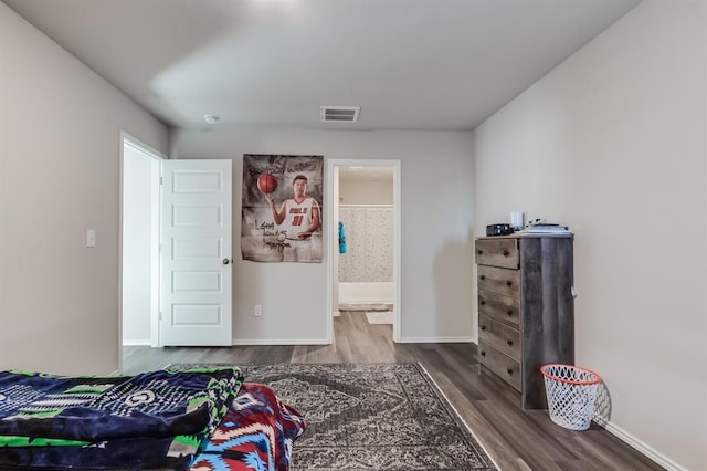 bedroom with ensuite bath and hardwood / wood-style flooring