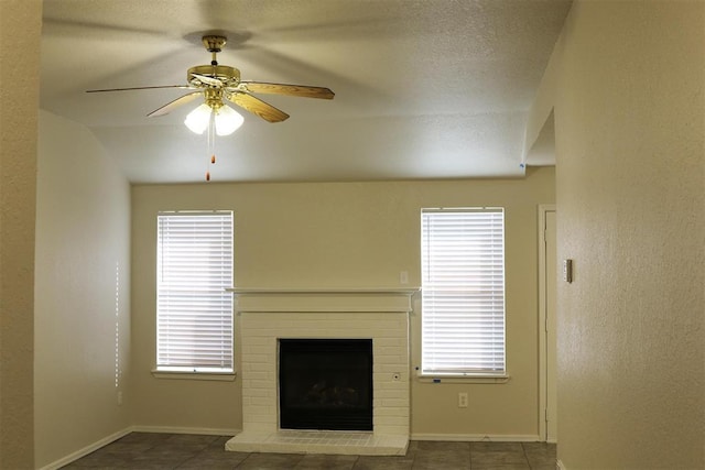 unfurnished living room with a fireplace, plenty of natural light, ceiling fan, and vaulted ceiling