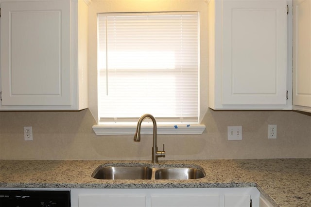 kitchen with white cabinetry, sink, light stone counters, and dishwashing machine