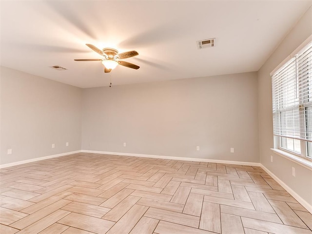 empty room with visible vents, a ceiling fan, and baseboards