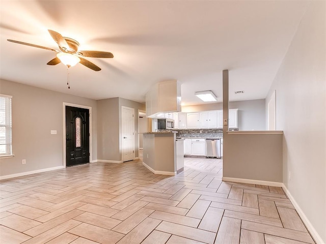kitchen with a ceiling fan, appliances with stainless steel finishes, baseboards, and white cabinetry