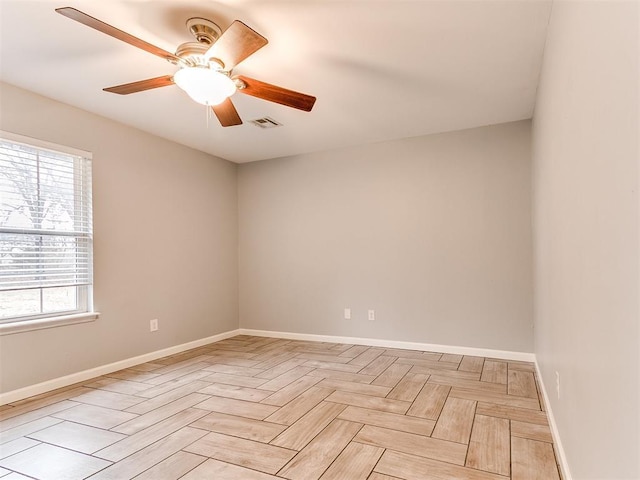 empty room featuring baseboards, visible vents, and ceiling fan