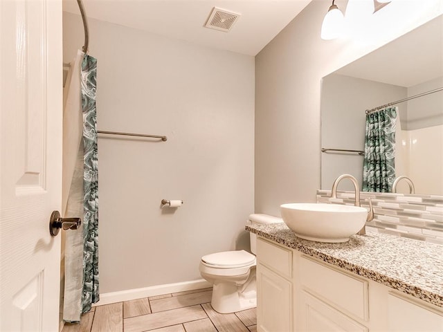 bathroom featuring backsplash, visible vents, toilet, vanity, and baseboards