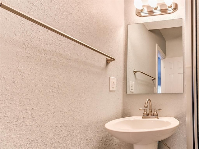 bathroom featuring a textured wall and a sink