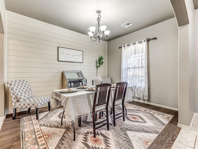 dining room with a chandelier and wood walls