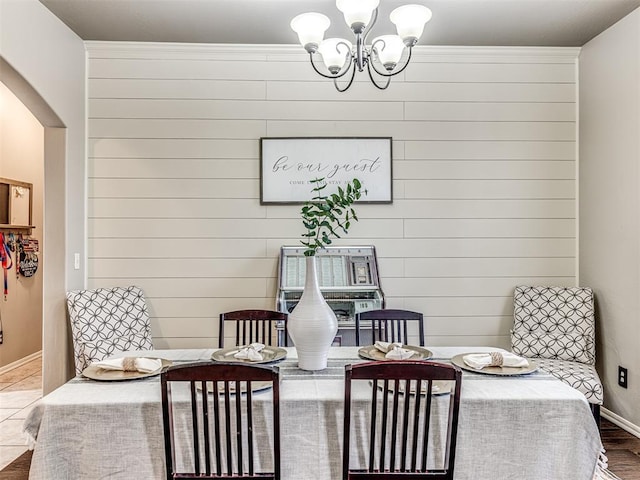 dining area with an inviting chandelier, hardwood / wood-style flooring, and wood walls