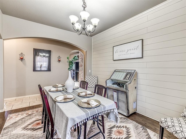 dining area with dark hardwood / wood-style floors, a chandelier, and wood walls