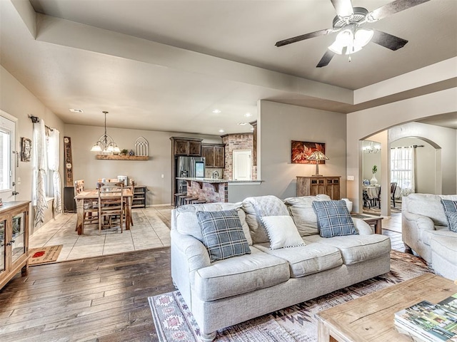 living room with ceiling fan with notable chandelier and light hardwood / wood-style flooring