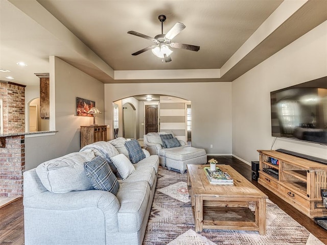 living room with dark hardwood / wood-style flooring, ceiling fan, and a tray ceiling