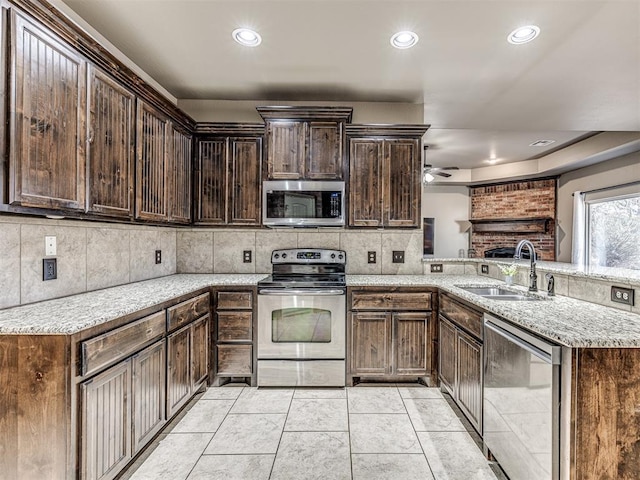 kitchen with sink, light tile patterned floors, appliances with stainless steel finishes, dark brown cabinetry, and light stone counters