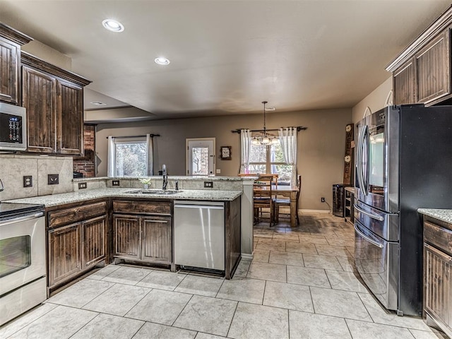 kitchen with sink, appliances with stainless steel finishes, dark brown cabinetry, decorative backsplash, and kitchen peninsula