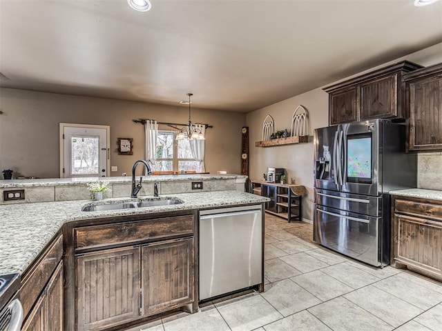 kitchen featuring light tile patterned flooring, dark brown cabinetry, sink, hanging light fixtures, and appliances with stainless steel finishes