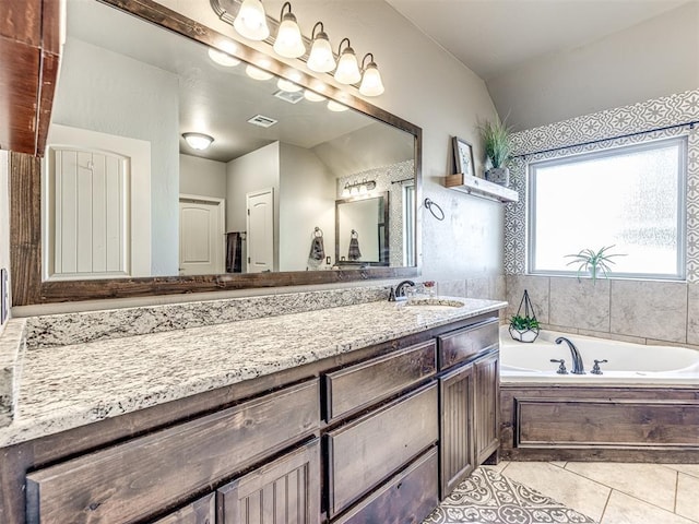 bathroom featuring tile patterned flooring, vanity, vaulted ceiling, and a bathing tub