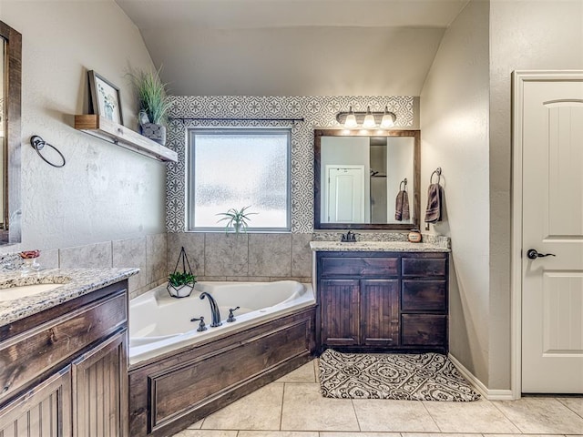 bathroom featuring vanity, lofted ceiling, a bath, and tile patterned floors