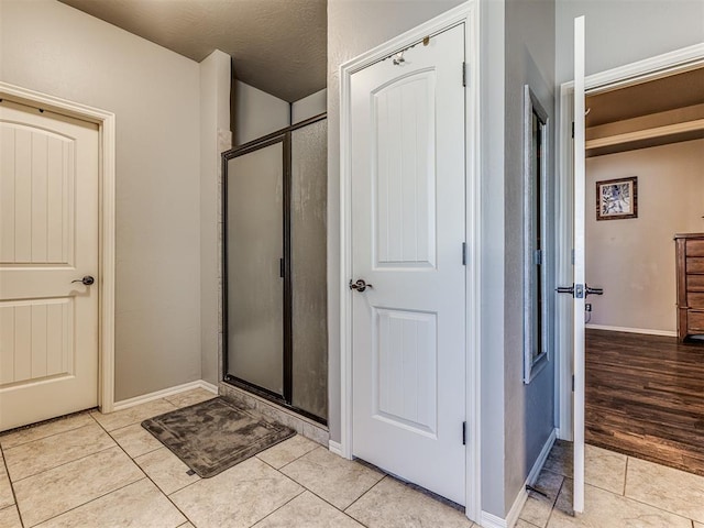 bathroom featuring tile patterned flooring, a textured ceiling, and a shower with shower door