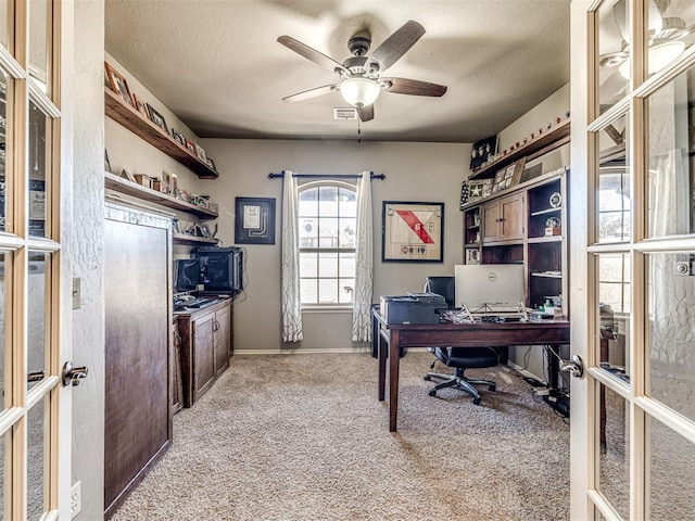 carpeted office space with a textured ceiling, ceiling fan, and french doors