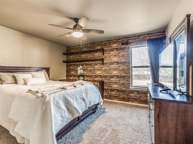 carpeted bedroom with ceiling fan and wood walls