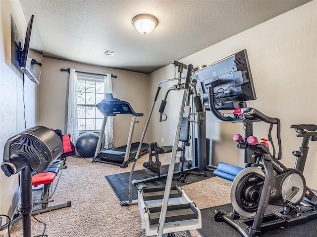 exercise area with carpet floors and a textured ceiling