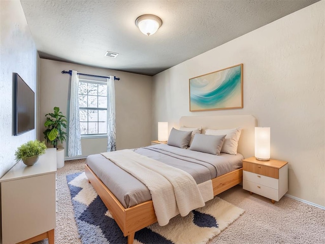 bedroom featuring light colored carpet and a textured ceiling