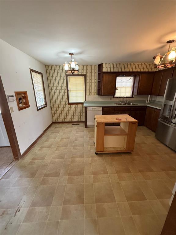 kitchen featuring sink, a notable chandelier, white dishwasher, and stainless steel fridge with ice dispenser