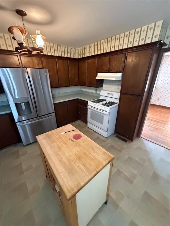 kitchen featuring dark brown cabinetry, stainless steel fridge with ice dispenser, tasteful backsplash, and gas range gas stove