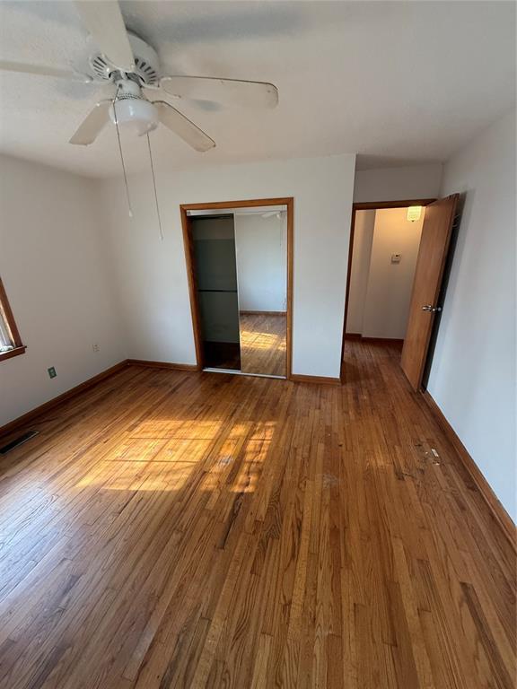 unfurnished bedroom with hardwood / wood-style flooring, ceiling fan, and a closet