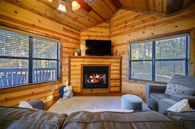 living room featuring lofted ceiling, plenty of natural light, and wood walls