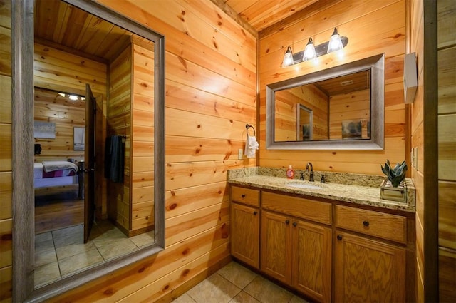 bathroom featuring tile patterned floors, vanity, and wood walls