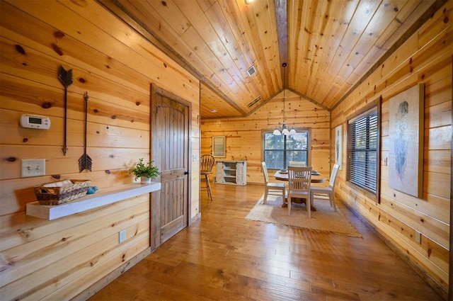 dining room with lofted ceiling, wood ceiling, light hardwood / wood-style flooring, an inviting chandelier, and wood walls