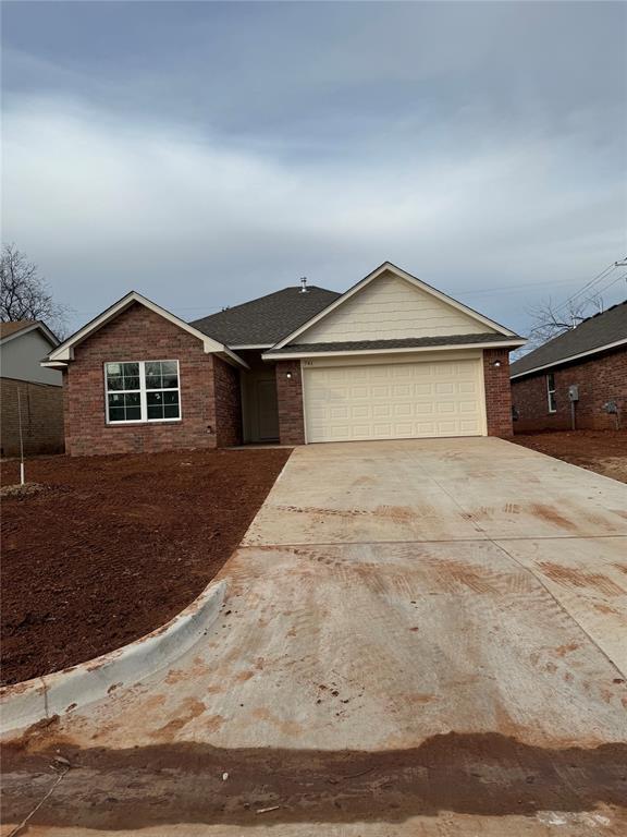 ranch-style house featuring an attached garage, concrete driveway, and brick siding