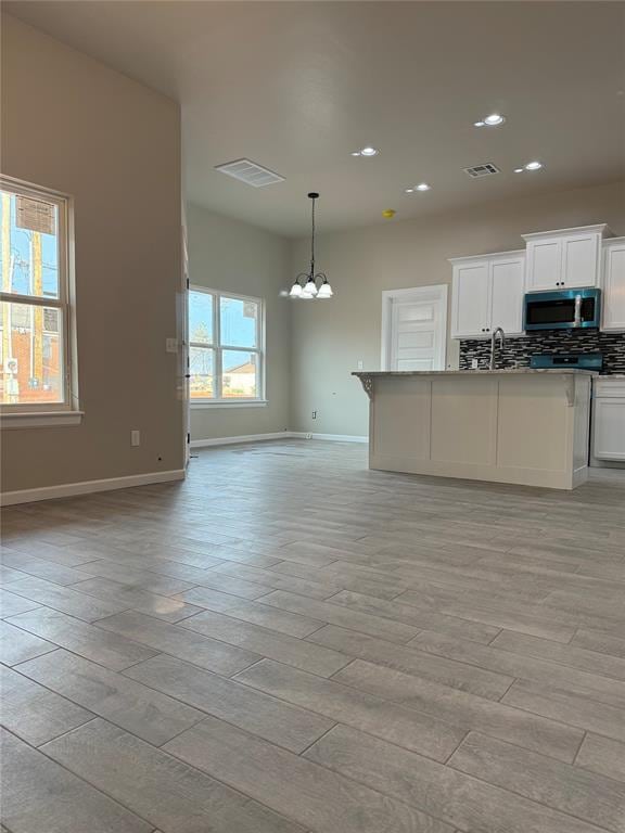 kitchen featuring pendant lighting, white cabinetry, tasteful backsplash, light hardwood / wood-style floors, and a chandelier