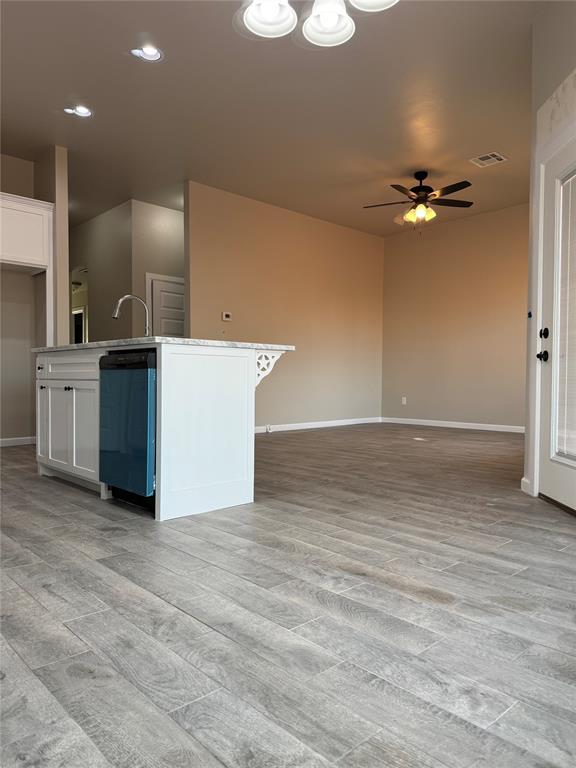 kitchen with a center island with sink, light wood-type flooring, dishwasher, ceiling fan, and white cabinets