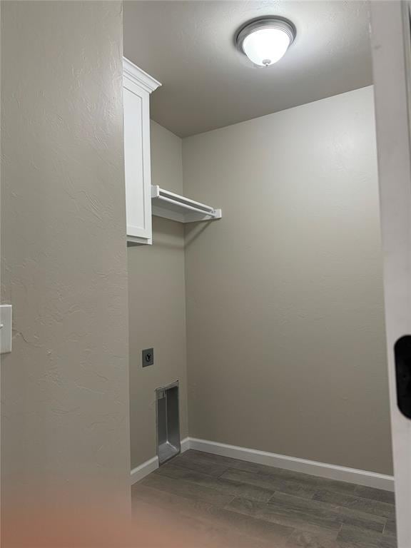 washroom with electric dryer hookup, dark hardwood / wood-style flooring, and cabinets